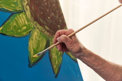 A hand painting a sunflower.