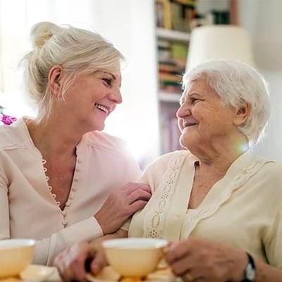 Two women enjoying tea and conversation in a cozy setting.