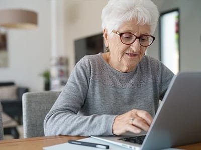 Senior woman using a laptop in an indoor setting.
