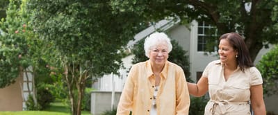 Senior woman walking with staff in garden area
