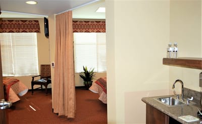Bright shared living space with two beds and kitchenette.