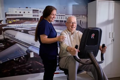 Staff assisting a resident on exercise equipment