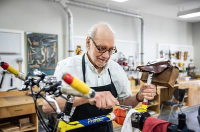 An elderly man repairing a bicycle in a workshop