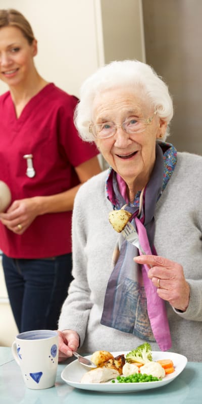 A resident enjoying a meal with staff member in a dining area