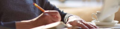 A close-up of a person writing at a table.