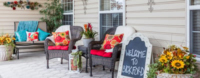 Cozy outdoor seating area with flowers and welcome sign