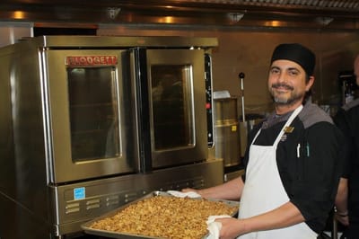 Cook presenting a tray of prepared food in the kitchen