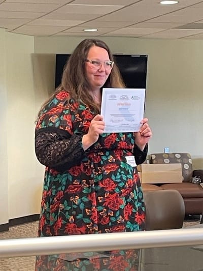 Staff member celebrating with recognition certificate inside the facility