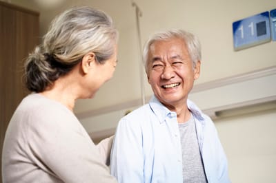 Two seniors enjoying a joyful moment in a facility hallway