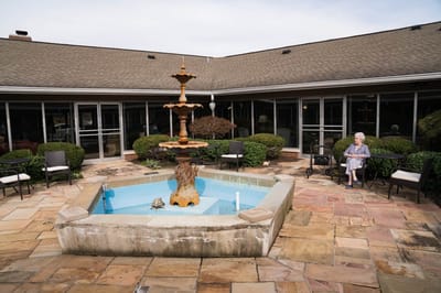 A serene outdoor courtyard with a fountain and a resident sitting