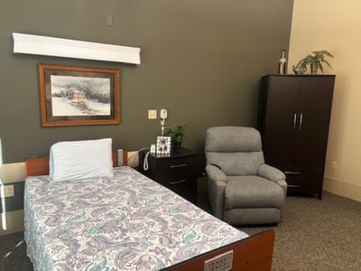 A cozy resident room with bed and armchair