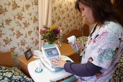 Nurse operating medical equipment in a resident's room