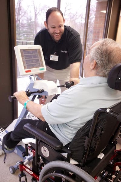 Staff member assisting a resident with a rehabilitation machine