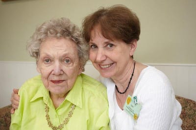 A caregiver and resident smiling together in an interior setting