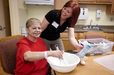 Staff assisting a resident in a cooking activity