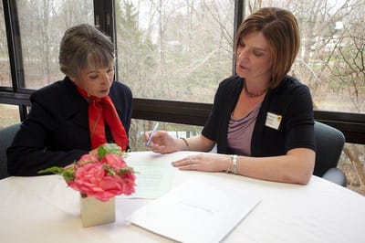 Staff assisting a resident with paperwork in a well-lit room