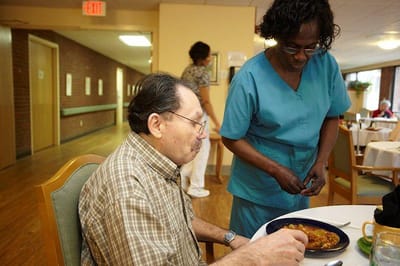 Resident enjoying a meal with staff assistance