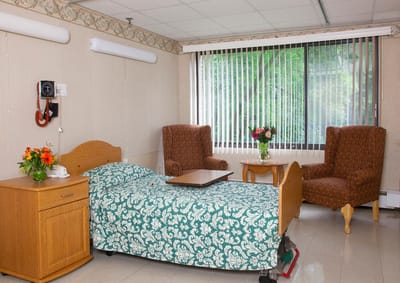 A well-furnished private resident room with a bed and seating area