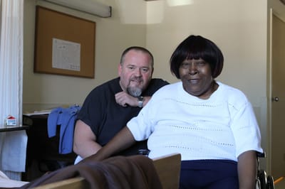 A staff member and resident smiling in an indoor setting