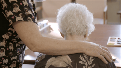 Close-up of a caregiver comforting a senior resident.