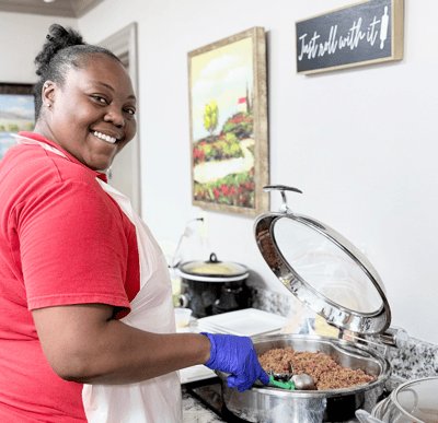 Staff member preparing food in kitchen area.