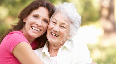 Happy woman and elderly resident embracing outdoors.