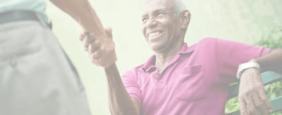An elderly man smiling while shaking hands.