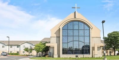 Exterior view of a facility with a cross and large windows.
