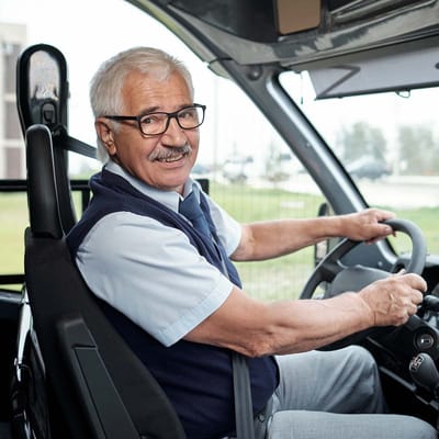 Senior gentleman driving a facility transport vehicle.