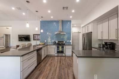 Modern kitchen with blue backsplash and sleek appliances.