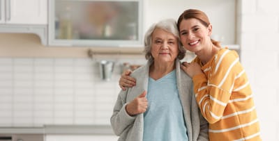 Senior woman and caregiver smiling together indoors