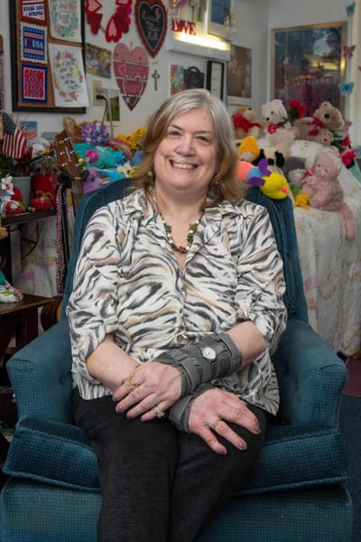 Smiling woman seated in a vibrant interior filled with stuffed animals.