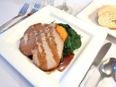 Plate of meat with greens and mashed sweet potato
