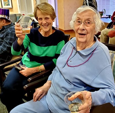 Two seniors enjoying a toast in a common area.