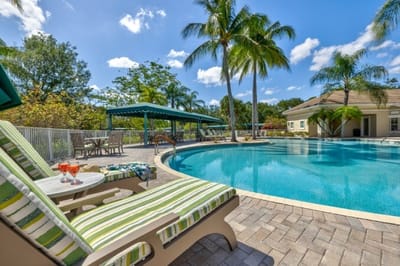 Poolside lounge chairs with palm trees and clear sky