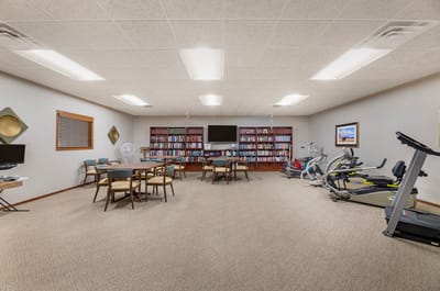 Interior activity room with exercise equipment and bookshelves
