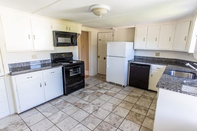 Clean kitchen area with white cabinetry and appliances