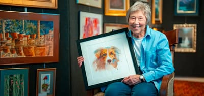 Resident holding a framed painting, smiling