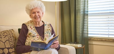 Senior resident reading a book in a cozy lounge area