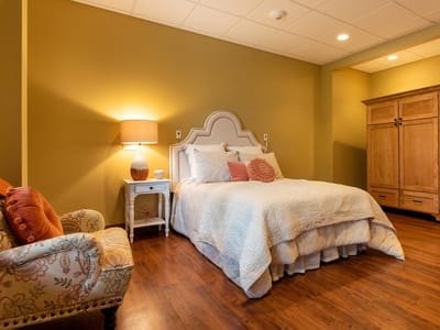 A well-furnished private resident room with a bed and seating area