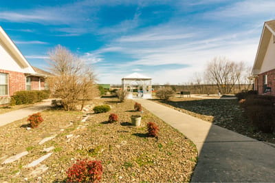 A serene outdoor pathway with a gazebo and garden beds