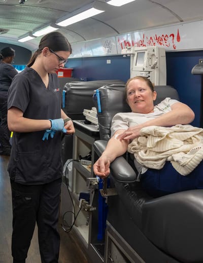 Nurse assisting a resident with an IV in a medical setting