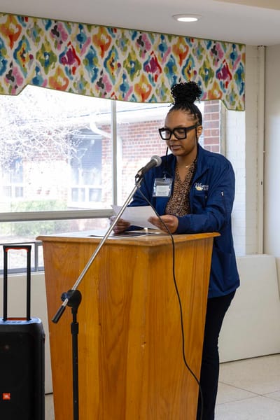 Staff member speaking at a podium in a common area