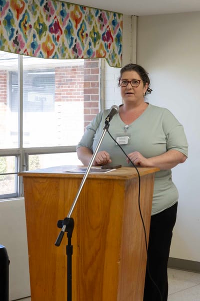 Staff member speaking at a podium in a common area