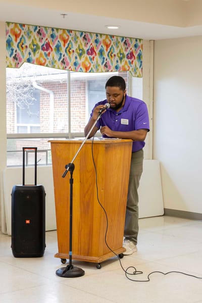 A staff member speaking at a podium in a common area