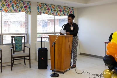 Staff member speaking at a community event in a common area