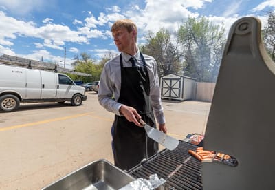 Staff member grilling sausages outdoors at the facility