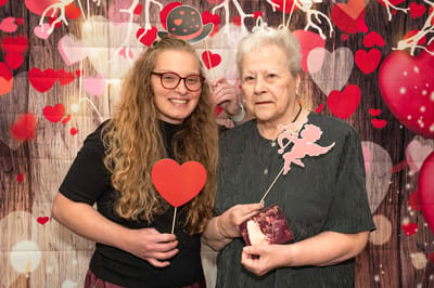 Resident and staff member posing with heart props