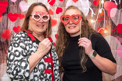 Two women celebrating with fun photo props.