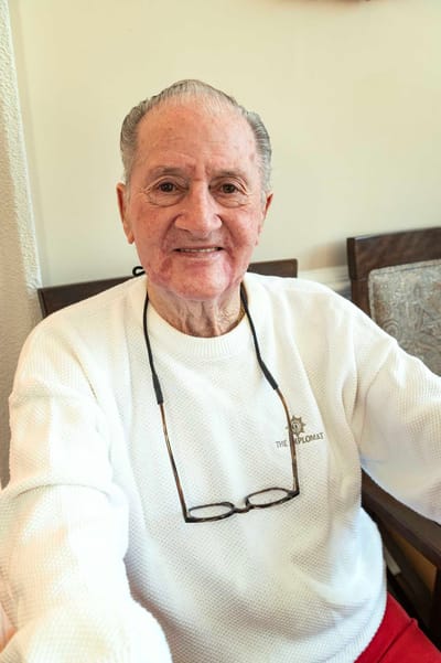 Elderly man smiling in a white sweater